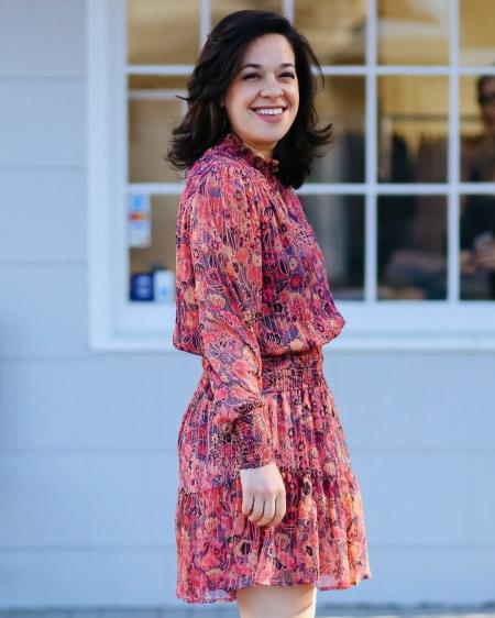 Dark haired girl smiles in her pink dress.