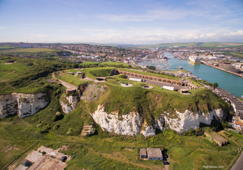 Aerial view of the grounds and red brick buildings of Newhaven Fort with sea in the distance