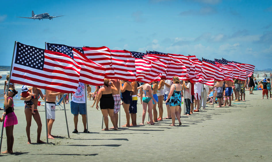 Beachgoers lined up with American Flags watching the military flyover