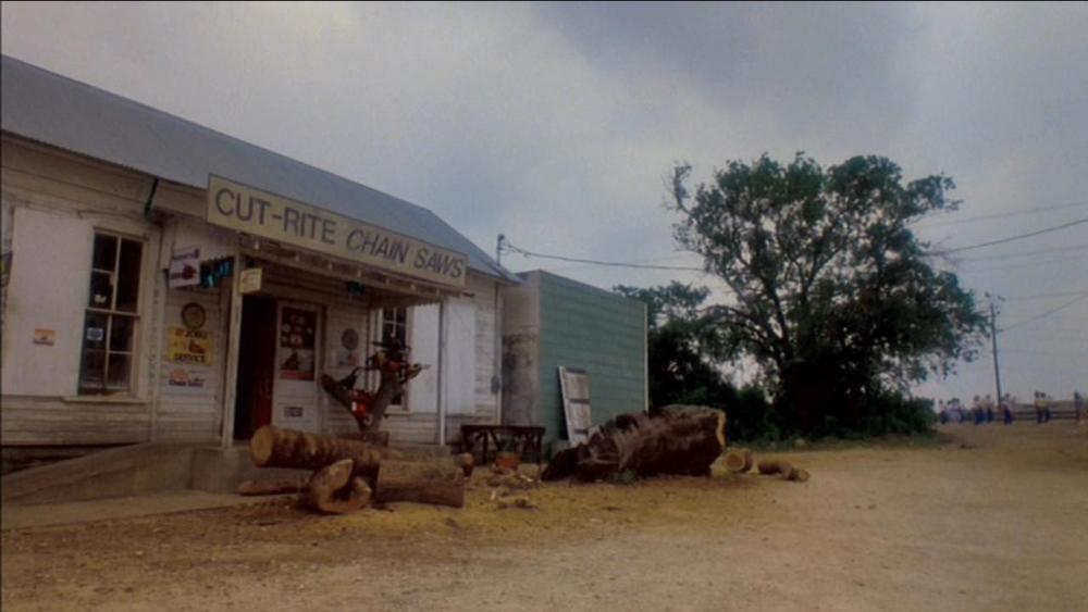 Texas Chainsaw Massacre 2 screengrab, showing the exterior of an old building with a sign reading Cut Rite Chainsaws