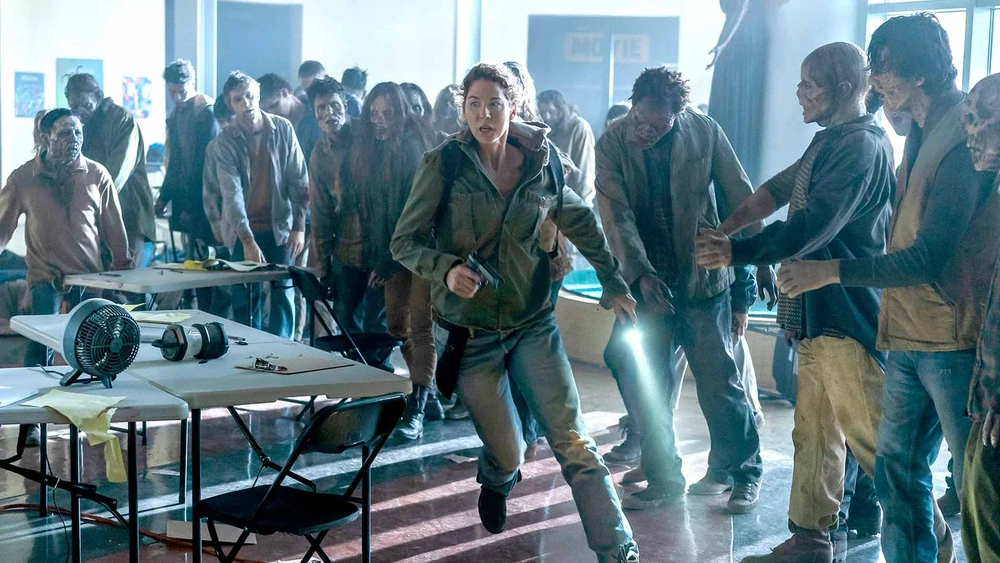 Fear the Walking Dead screengrab showing a group of zombies inside the FEMA Shelter as a woman with a handgun runs away