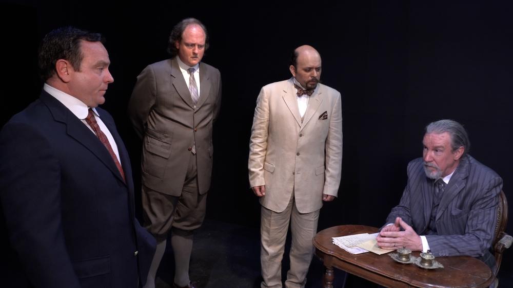 Agatha Christie's The Mysterious Affair at Styles, at Austin Playhouse. The photo pictures four men wearing suits, the man playing Hercule Poirot has a curled moustache