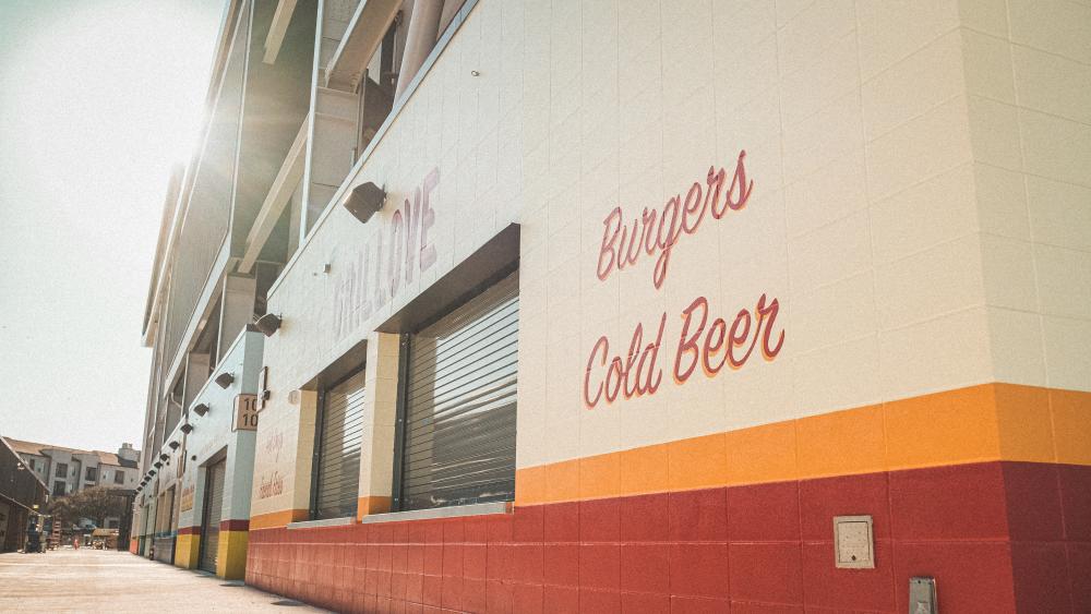Long row of vendor windows at Q2 Stadium, closest window has the words "Burgers" and "Cold Beer" painted on the wall next to it.