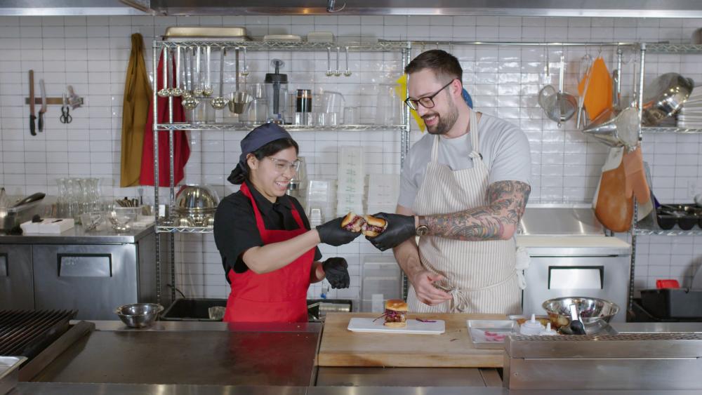 Culinary student and chef cheersing sliders they made together.