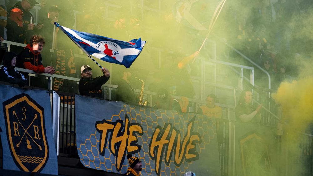 Fan waving a flag after a goal at a Fort Wayne Football Club match