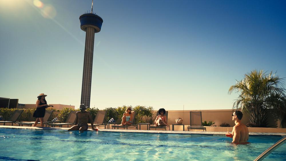 People enjoying pool with Tower of the Americas in distance