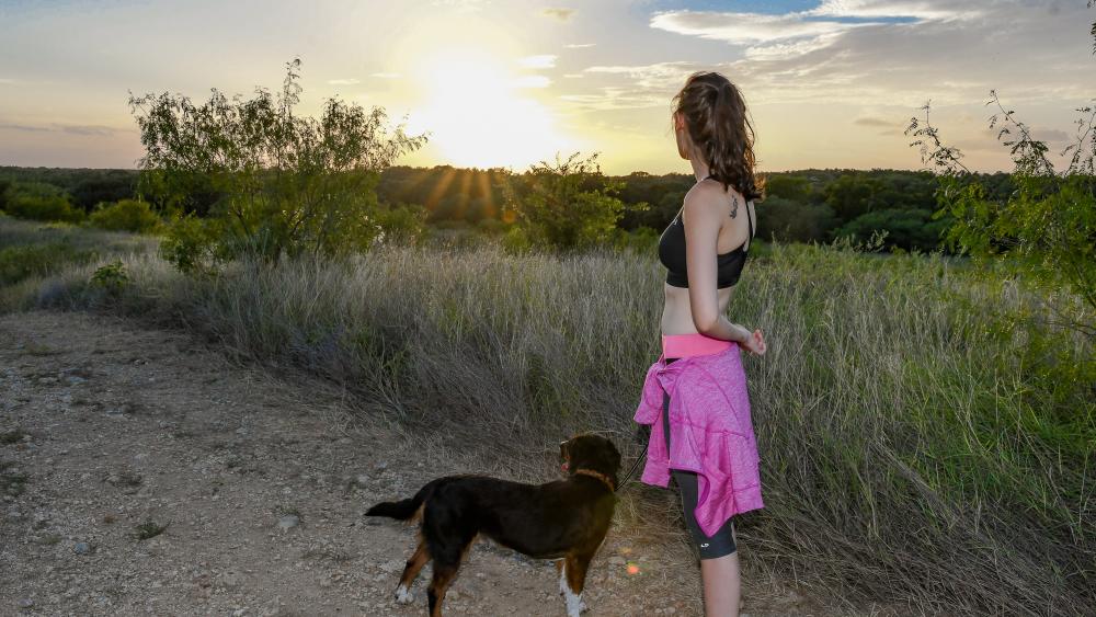 Girl with dog on trails at sunset