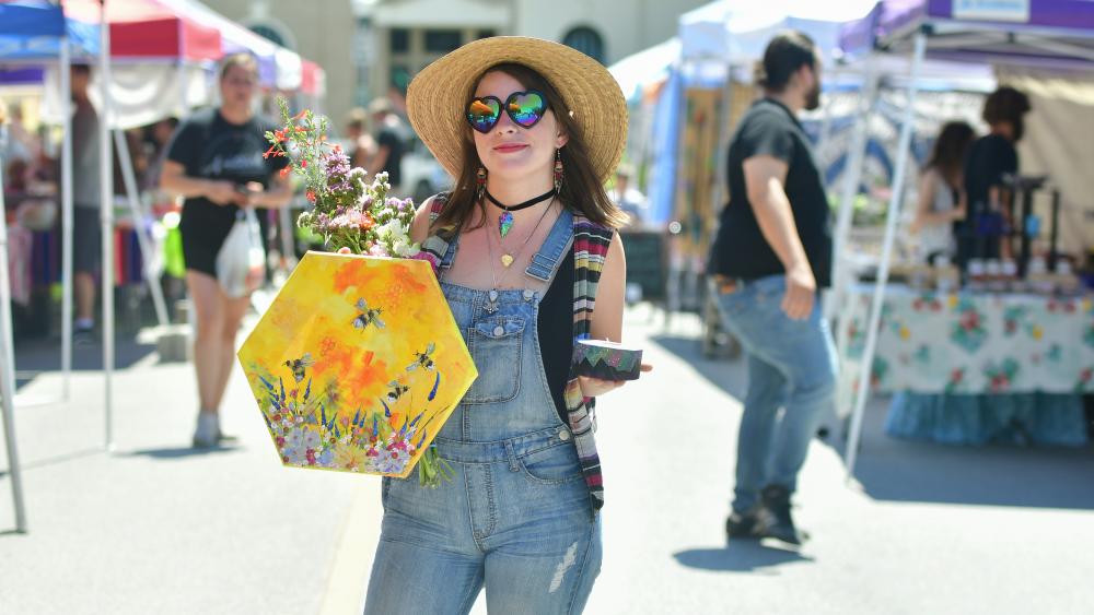 Woman at outdoor market with painting and flowers