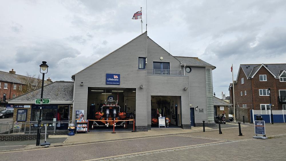Littlehampton Lifeboat Station - a cream building with a flag flying, the large entrance is open and shows the orange lifeboat inside