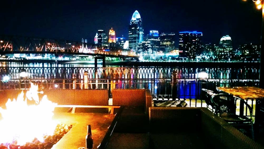 Fire burning on patio of Bar Louie with Cincy skyline in the background