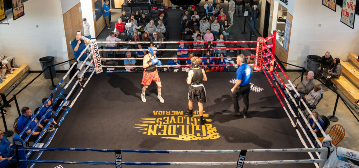 Two athletes are boxing inside a ring with an audience