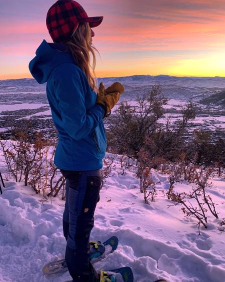 Woman watching the sun rise with a colorful sky in the background
