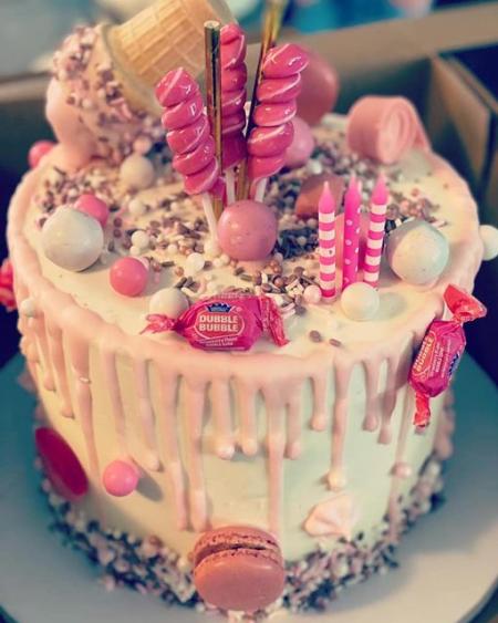 Pink cake with candy and cupcakes on top