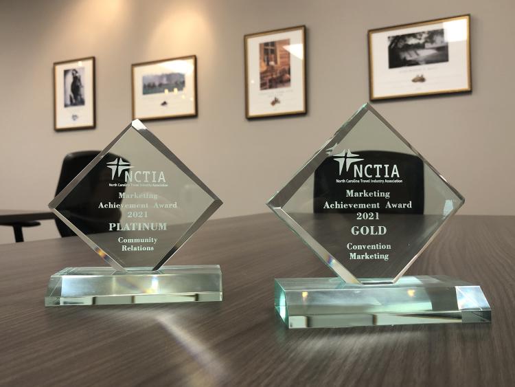 Two clear awards sit in a row on a conference table.