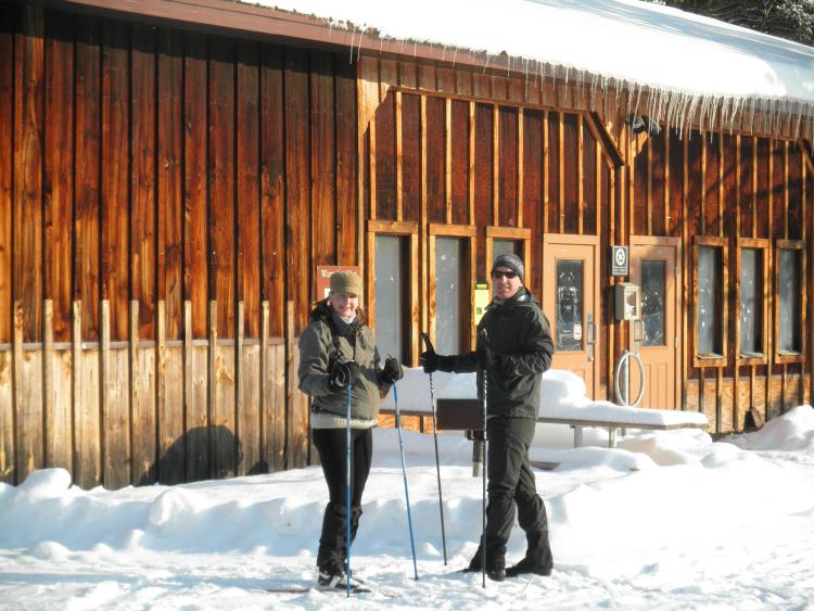Two x-country skiers standing in front of warming hut at Saratoga Spa State Park