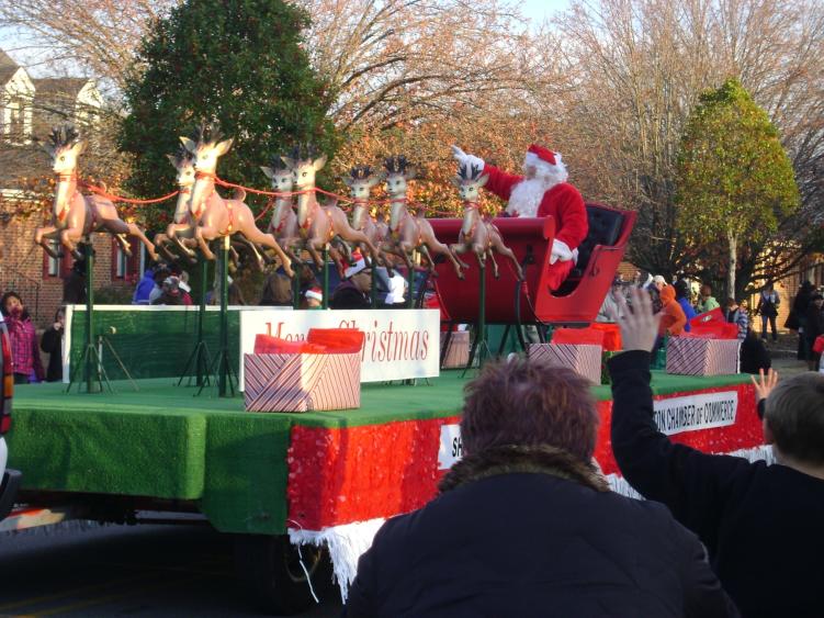 A parade float with Santa on his sleigh being pulled by reindeer in a Johnston County, NC parade.