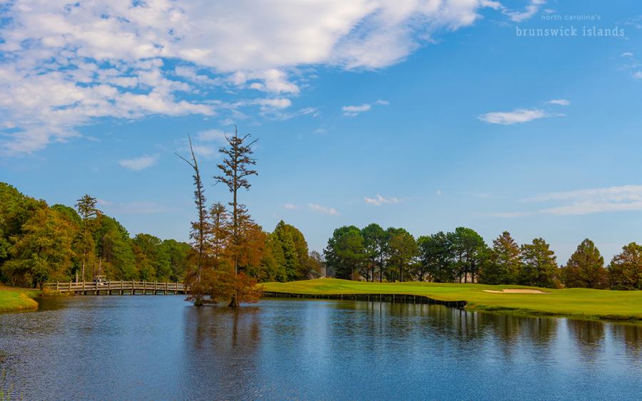 a golf course green surrounded by a body of water at Crow Creek Golf Club