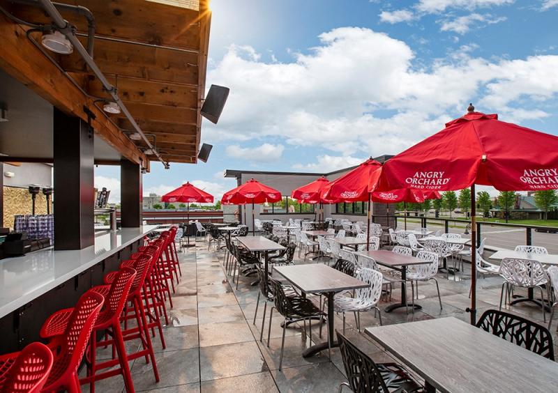 An outdoor bar with red metal chairs on the patio at CRAVE American Kitchen