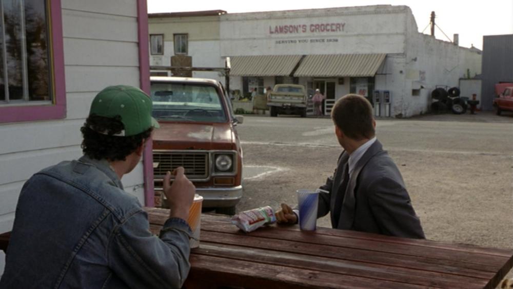 What's Eating Gilbert Grape Screengrab showing Johnny Depp and Leonardo DiCaprio being watched by friends as they load food bags into a pickup truck outside Lamson's Grocery