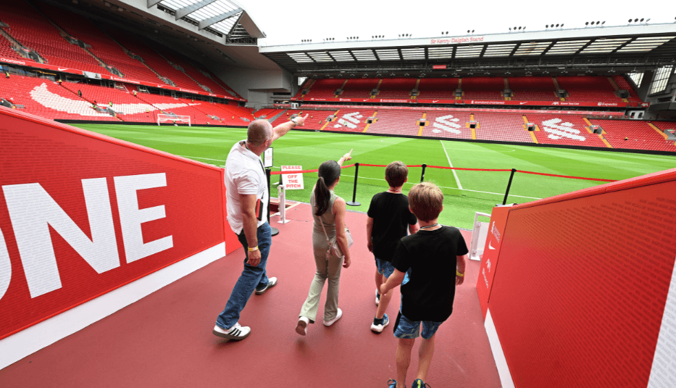 An adult and three children at the Anfield Stadium tour coming out of the players tunnel.