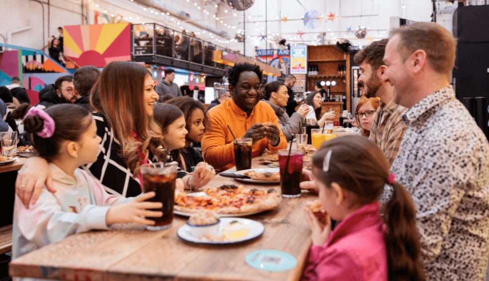 A group of families sitting at a long table eating food.