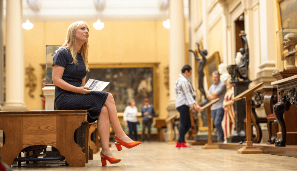 A woman sits in an ornate art gallery