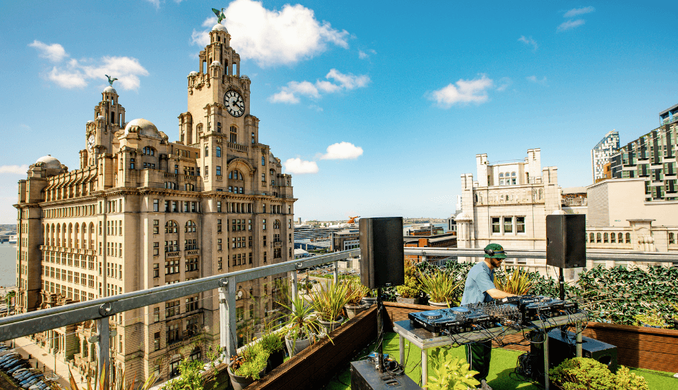 A DJ performing on the roof in front of the Royal Liver Building