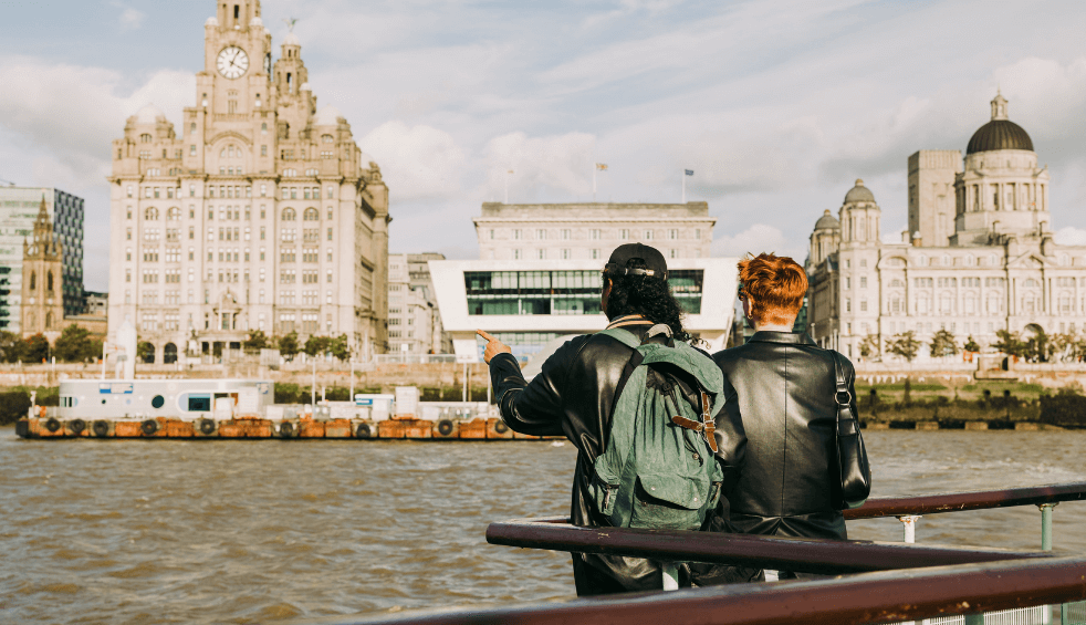 Two people sitting on the mersey ferry looking out at the skyline.