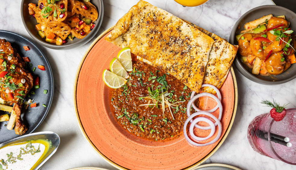 Plates on a table with different food dishes on including a curry.