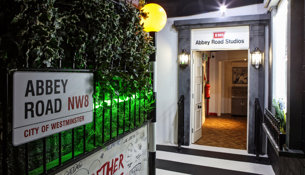 A recreation of Abbey Road in at The Beatles Story in Liverpool. There is an Abbey Road sign on a wall in front of a door that says Abbey Road Studios.