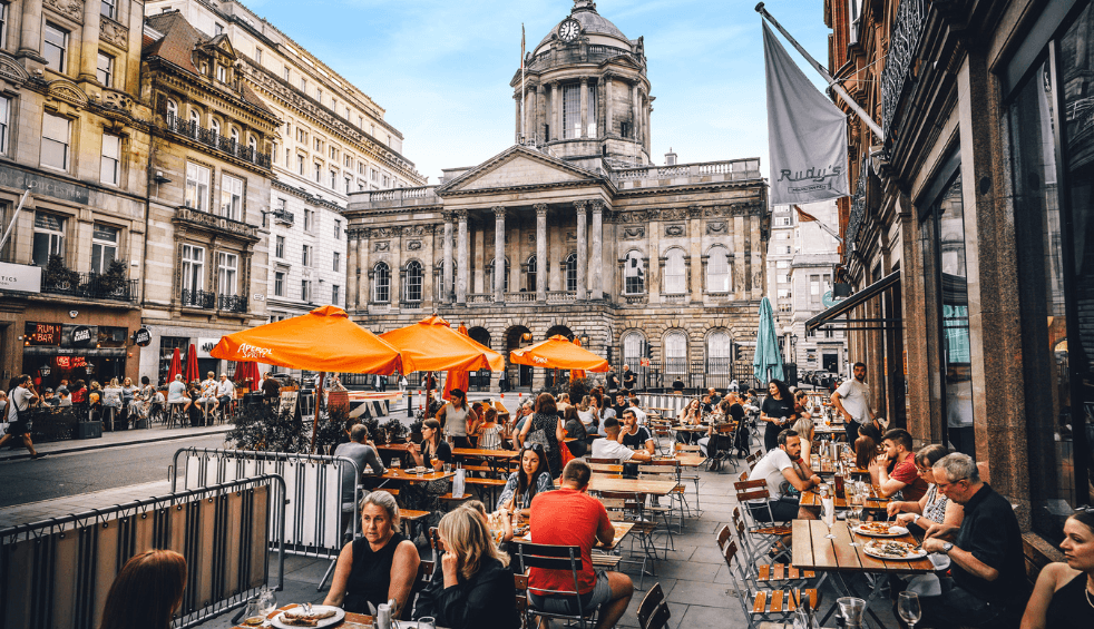People sitting out on tables in the street eating.