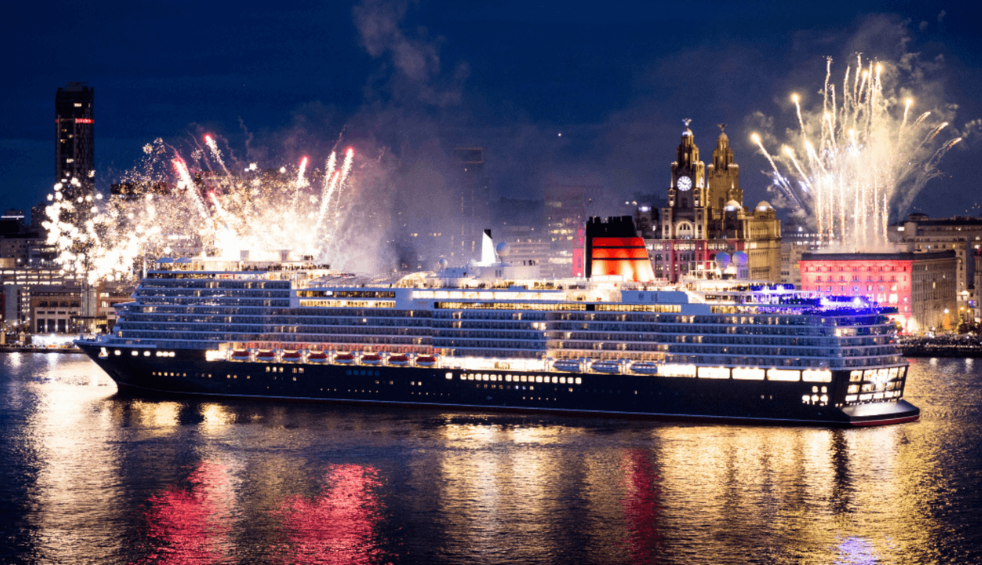 a Cunard ship on the River Mersey with fireworks coming from behind.