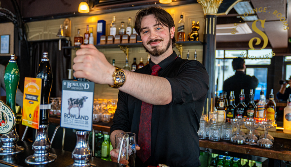 A person pulling a pint of beer in a bar.