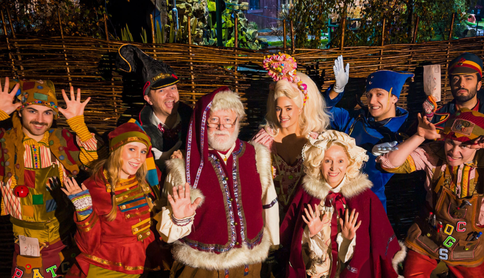 A group of people dressed in Christmas outfits with one person in the middle dressed as Father Christmas.