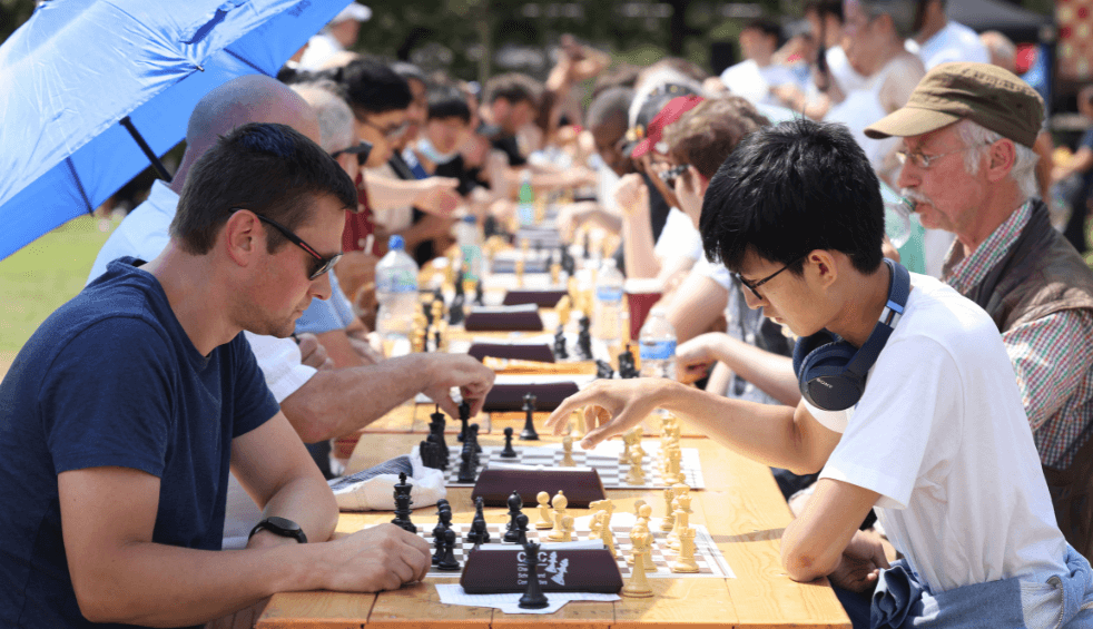 A row of chess tables with people playing chess.