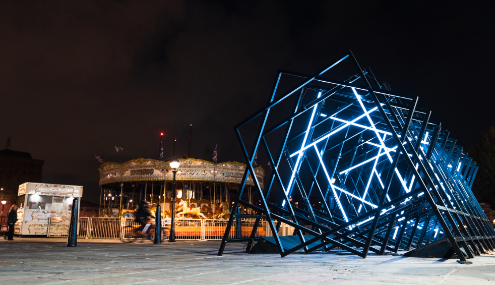 An art installation made up of a line of squares in different directions lit up blue.