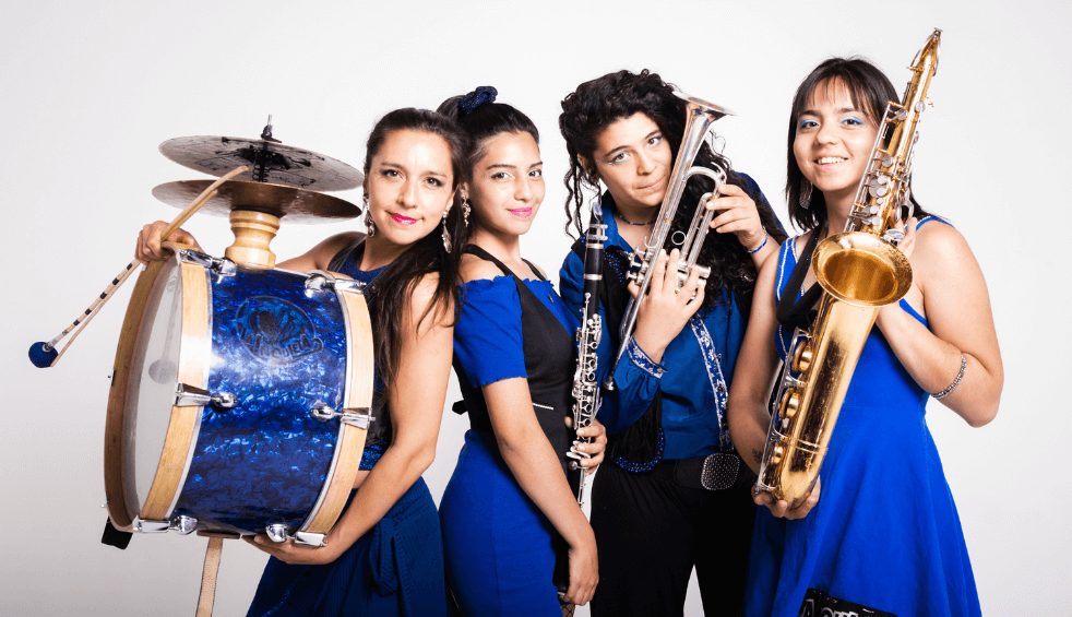 Four people wearing dark blue clothes holding instruments including a drum, a saxophone and other brass instruments.