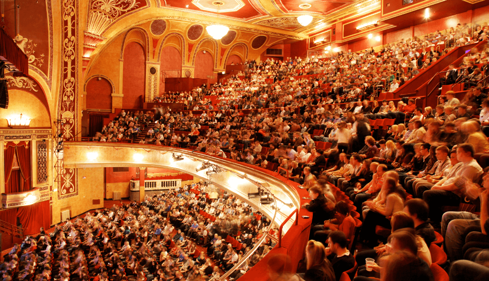 Inside a tiered, ornate theatre