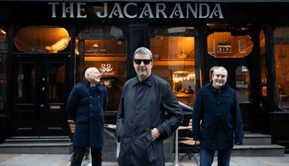 Three people stood outside the jacaranda