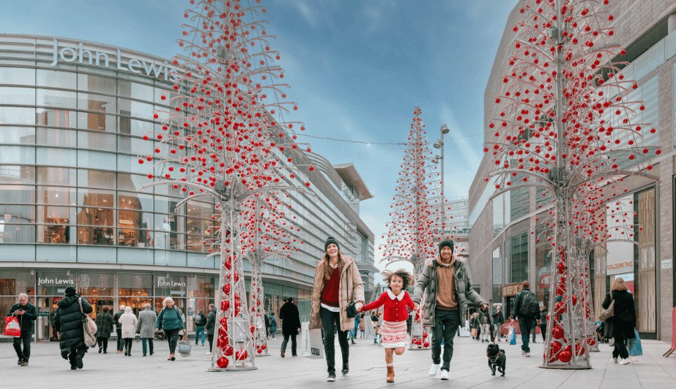 A family at Liverpool one with lit up trees around them.