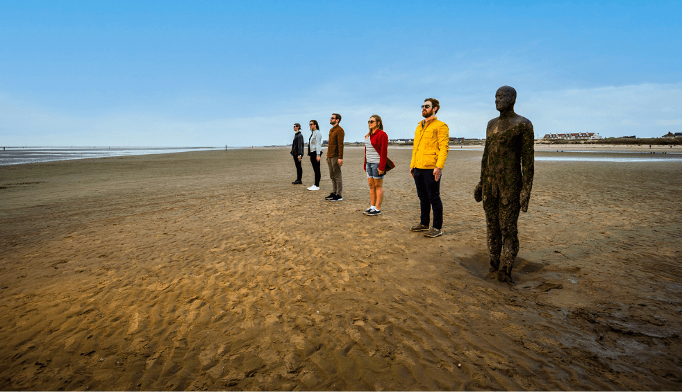 Anthony Gormley statue with four people trying to replicate the statue for a fun photo.