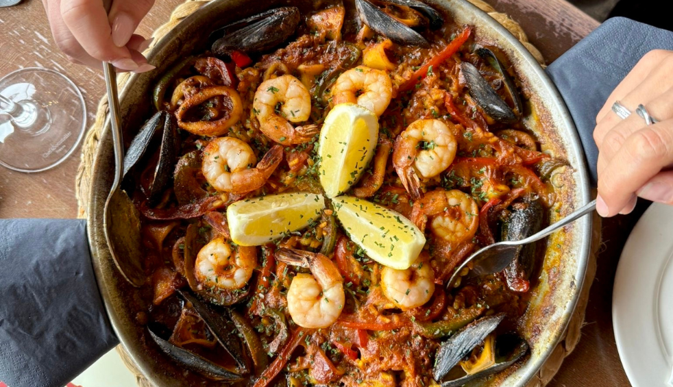 A big dish of rice, prawns, peppers and mussels, with slices of lemon in the middle.