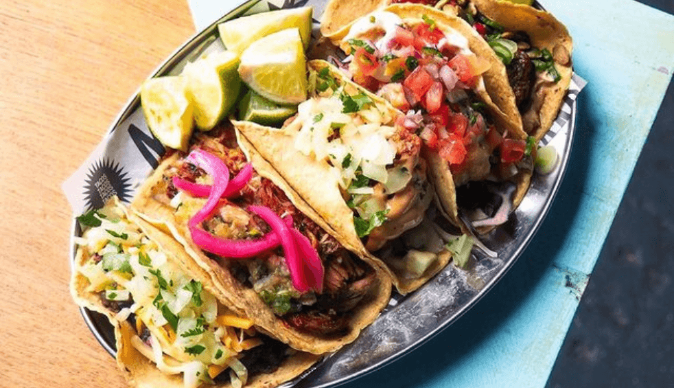 A plate of tacos on a tray on a table.
