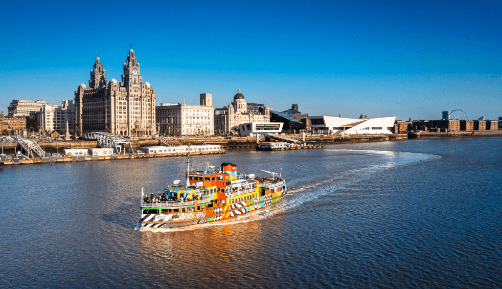 A ferry on the River Mersey with the Liverpool skyline behind it.