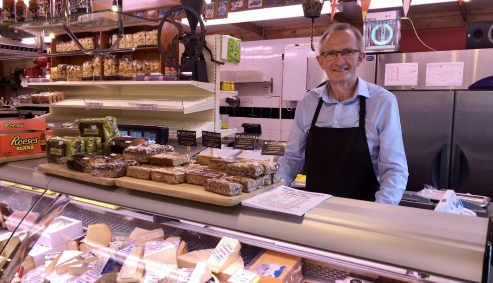A man standing behind a deli counter and smiling at the camera.