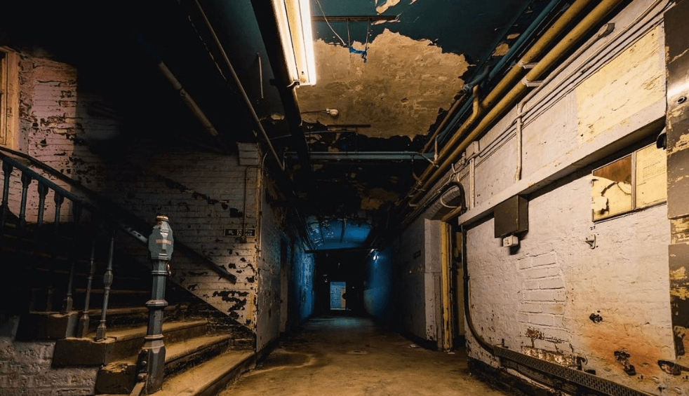Inside a derelict building with stairs to the left.