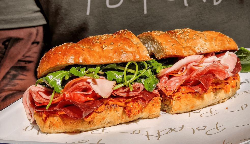A large subway style sandwich with a range of meats and salad.