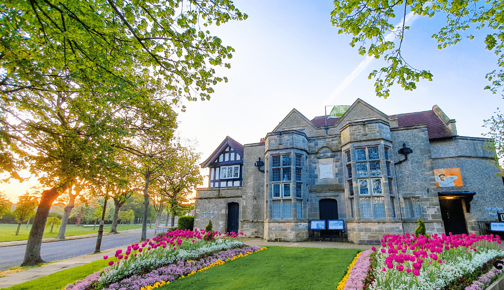 Outside of Port Sunlight museum with flowers in the front and a sunset in the background.
