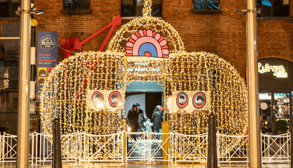 A large yellow submarine lit up with lights at the Royal Albert Dock