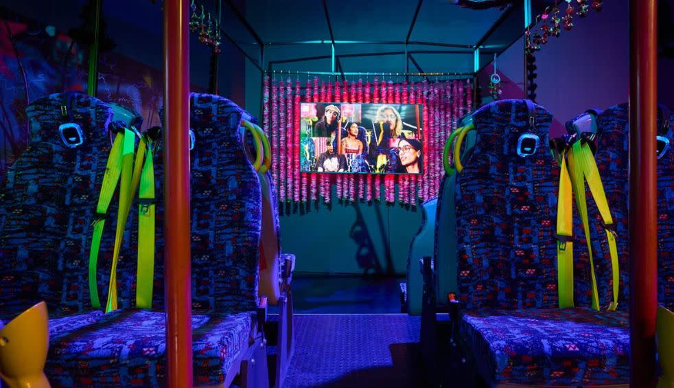 Inside an interactive art exhibition which looks like the inside of a busy under UV lights with a screen showing a video